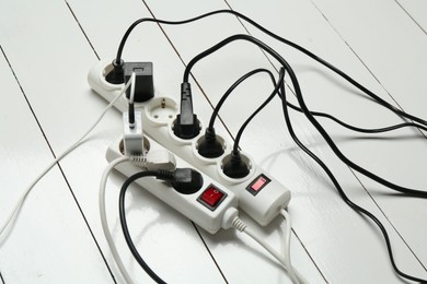 Photo of Extension power boards overloaded with plugs on wooden floor