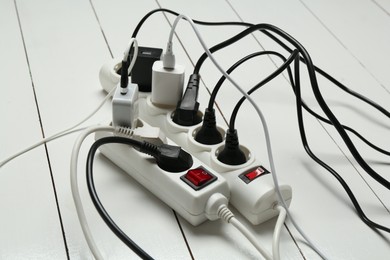 Photo of Extension power boards overloaded with plugs on wooden floor