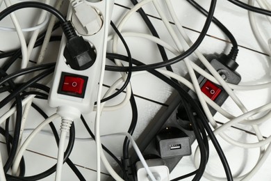 Photo of Extension power boards overloaded with plugs on wooden floor, closeup