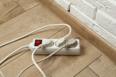 Photo of Extension power board overloaded with plugs on wooden floor