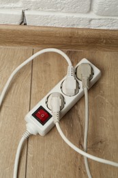 Photo of Extension power board overloaded with plugs on wooden floor, above view