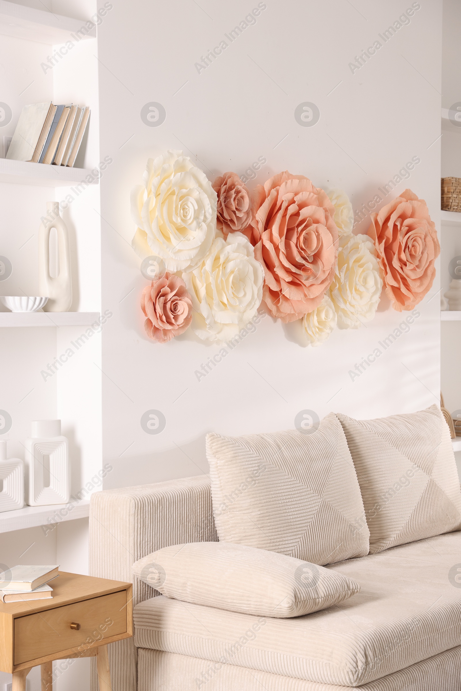 Photo of Beautiful decorative paper flowers on wall in room