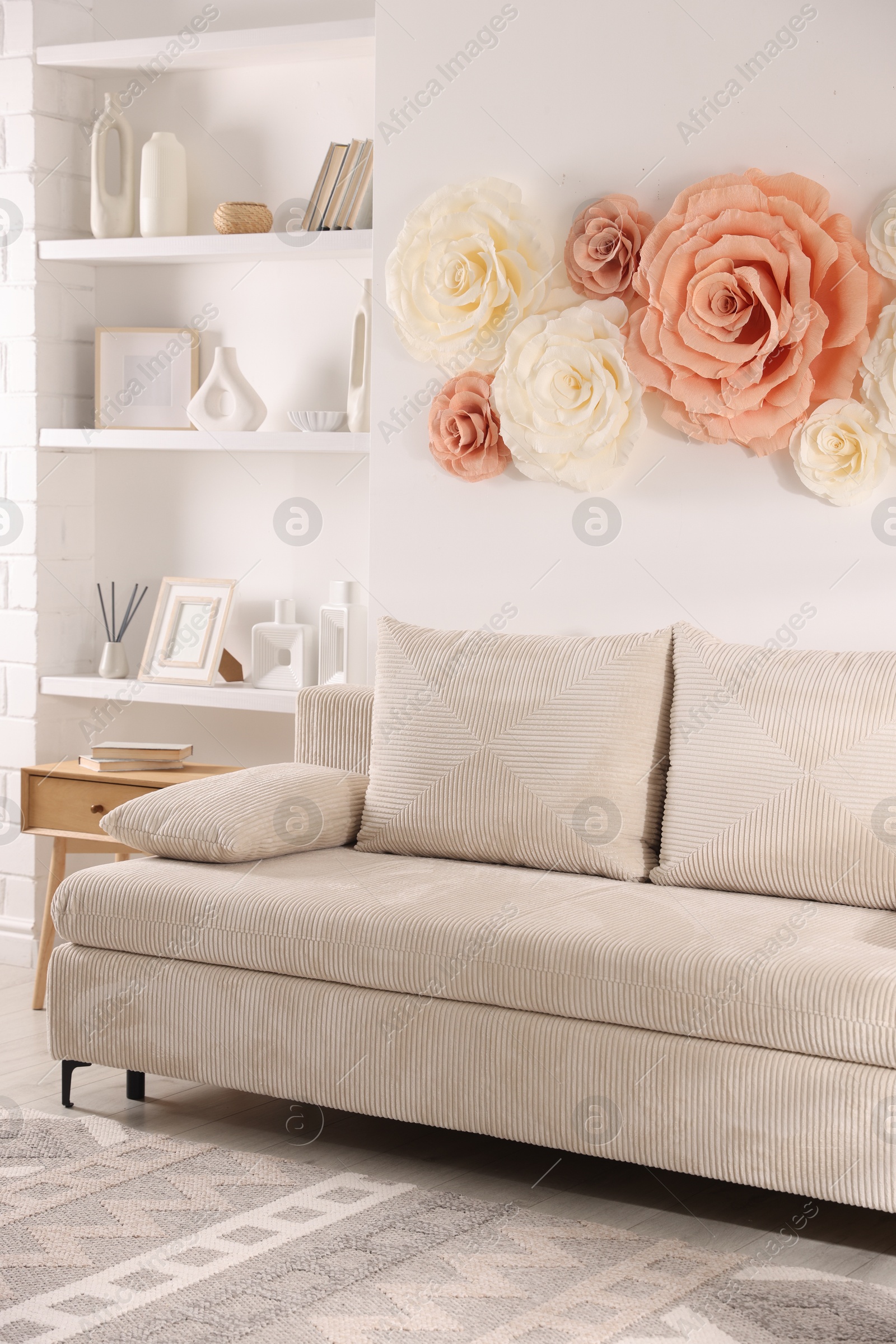 Photo of Beautiful decorative paper flowers on wall in room