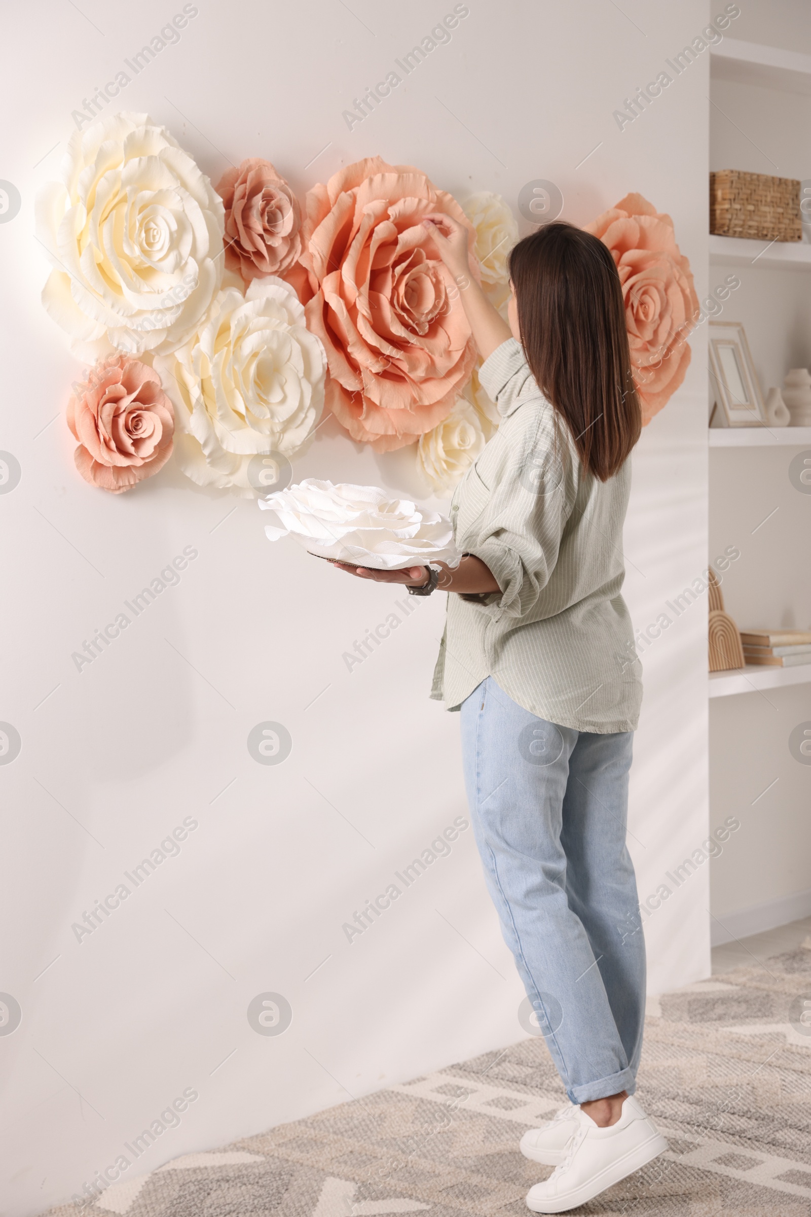 Photo of Woman decorating wall with beautiful paper flowers at home