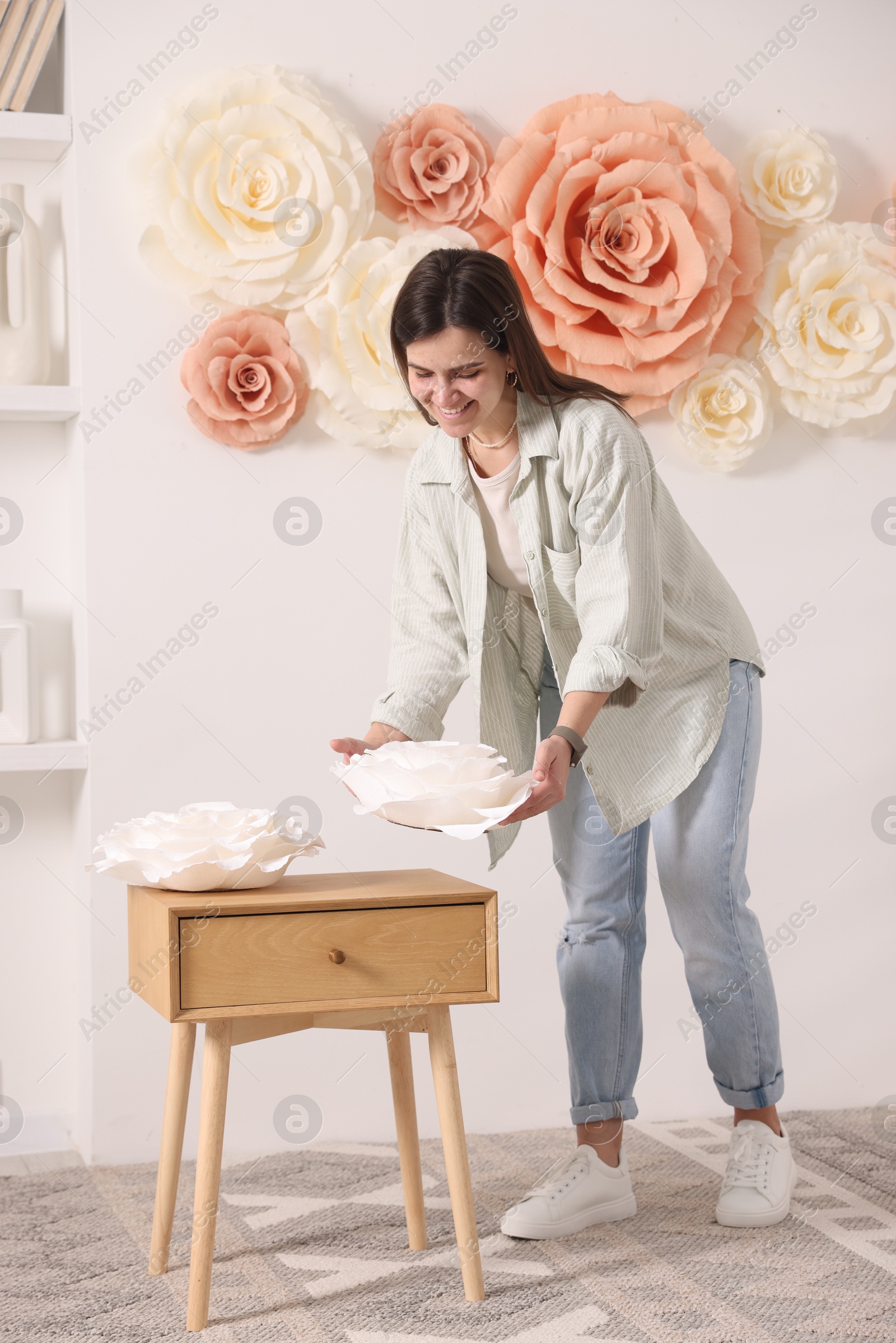 Photo of Woman decorating wall with beautiful paper flowers at home