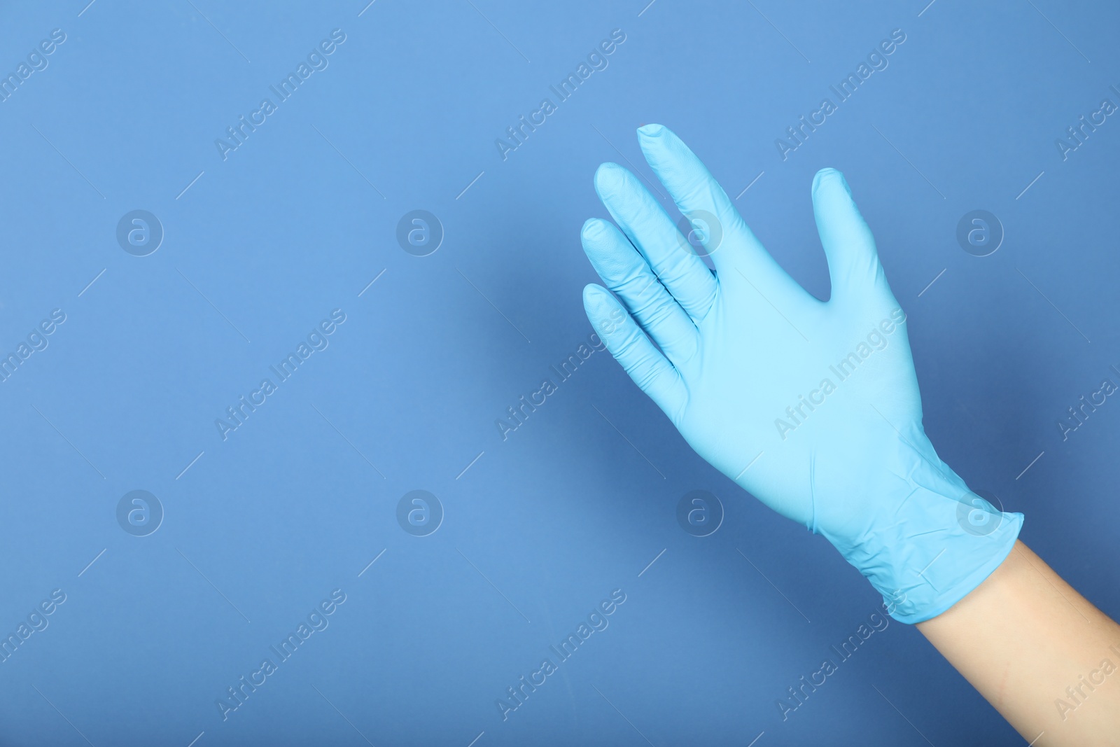 Doctor in medical glove on blue background, closeup. Space for text Photo of Doctor in medical glove on blue background, closeup. Space for text