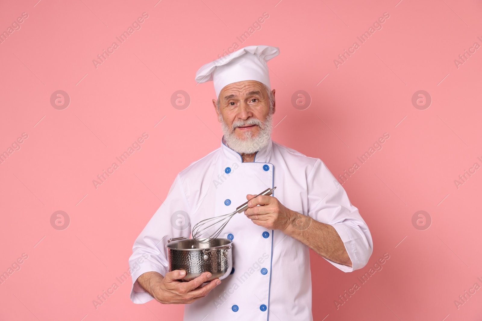 Photo of Professional pastry chef with whisk and cooking pot on pink background