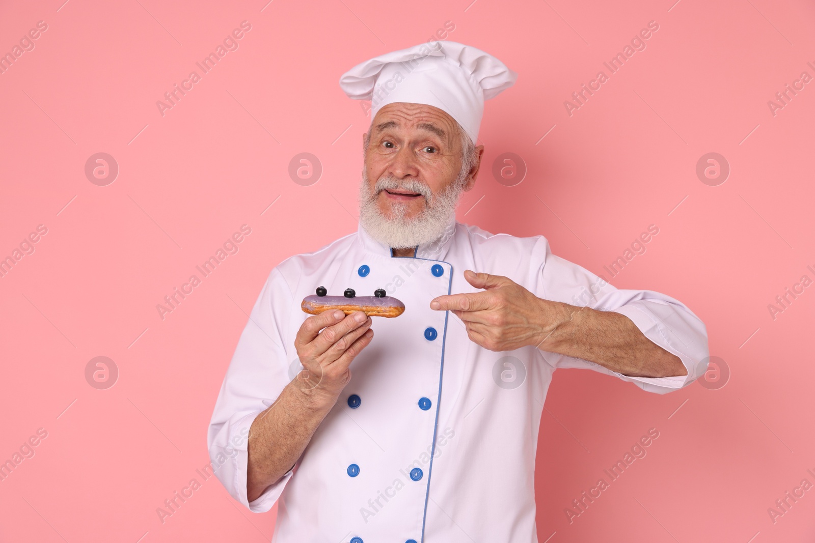 Photo of Professional pastry chef with delicious eclair on pink background