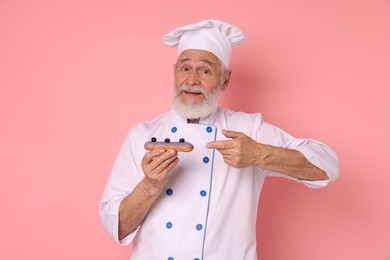 Professional pastry chef with delicious eclair on pink background