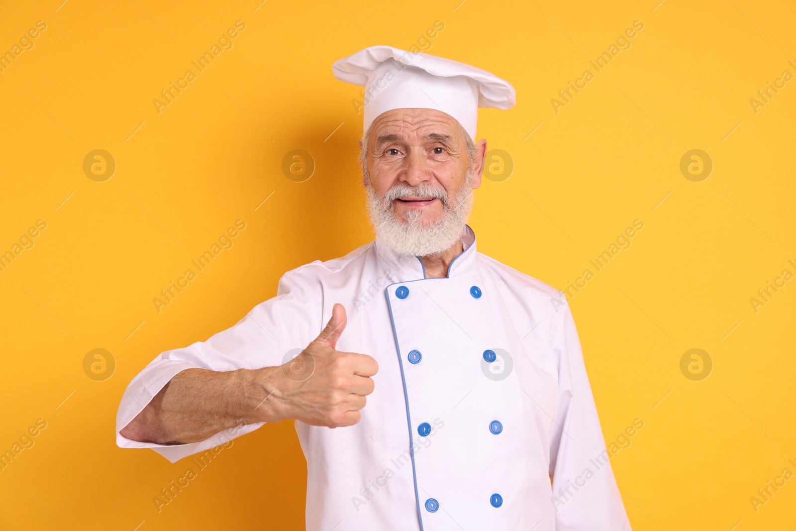 Photo of Professional pastry chef showing thumbs up on orange background