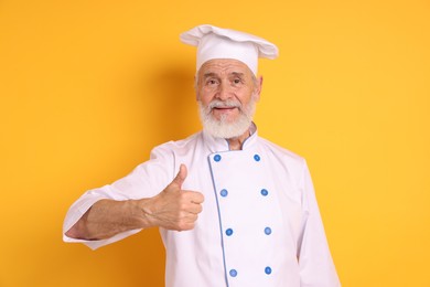 Photo of Professional pastry chef showing thumbs up on orange background