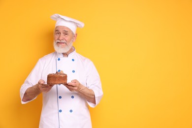 Professional pastry chef with delicious cake on orange background, space for text