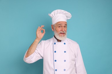 Photo of Professional pastry chef showing ok gesture on light blue background