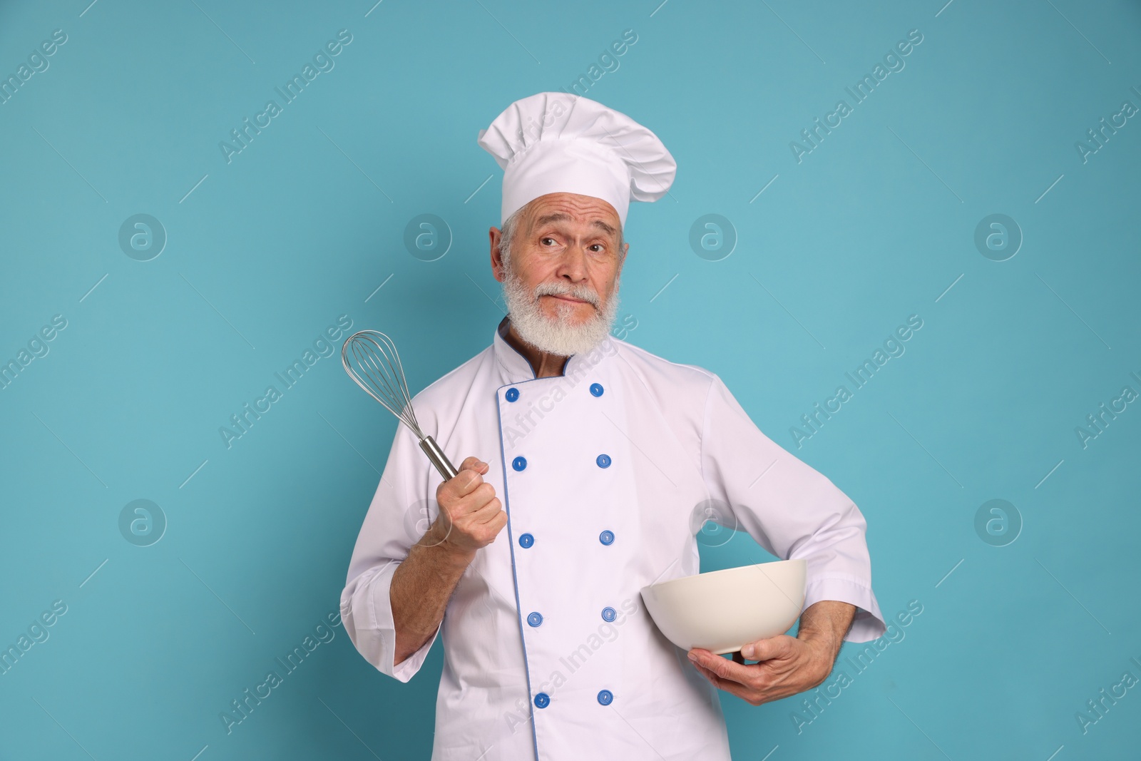 Photo of Professional pastry chef with whisk and bowl on light blue background