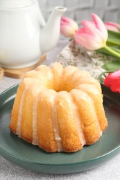 Photo of Delicious Easter bundt cake and tulips on grey table, closeup