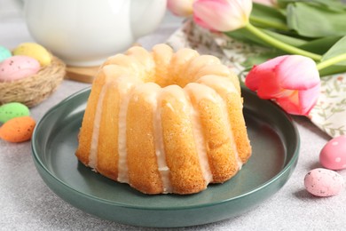 Photo of Delicious bundt cake, Easter eggs and tulips on grey table, closeup