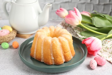 Photo of Delicious bundt cake, Easter eggs and tulips on grey table, closeup