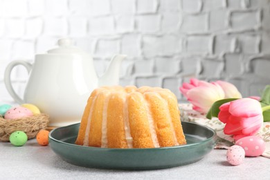 Photo of Delicious bundt cake, Easter eggs and tulips on grey table, closeup