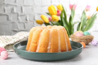 Photo of Delicious bundt cake, Easter eggs and tulips on grey table, closeup