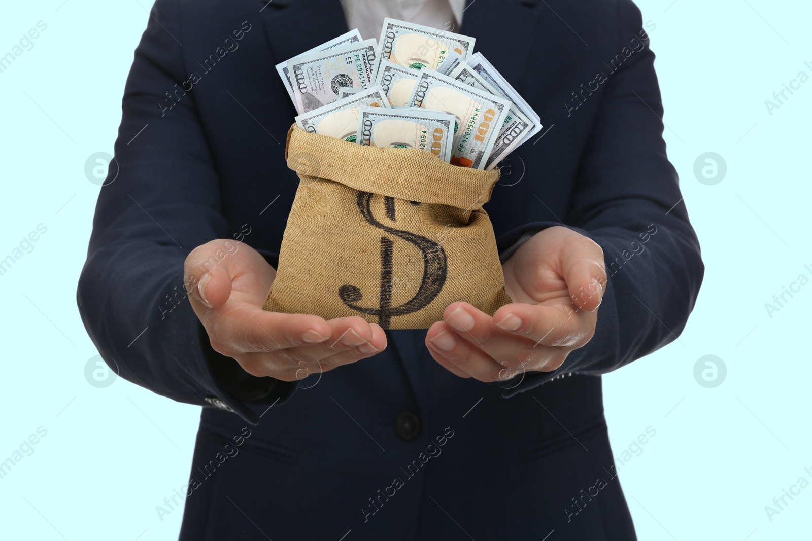 Image of Sponsor. Businessman holding sack with dollar banknotes on light blue background, closeup