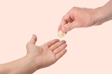 Sponsor giving coin to man on beige background, closeup