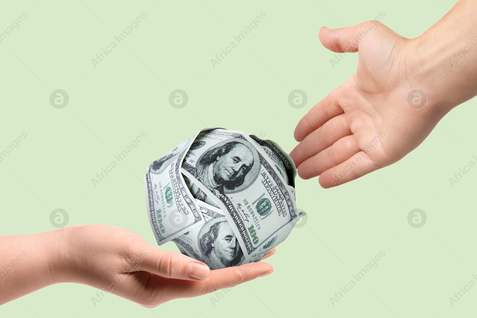 Image of Sponsor. Woman received ball of dollar banknotes from man on light green background, closeup