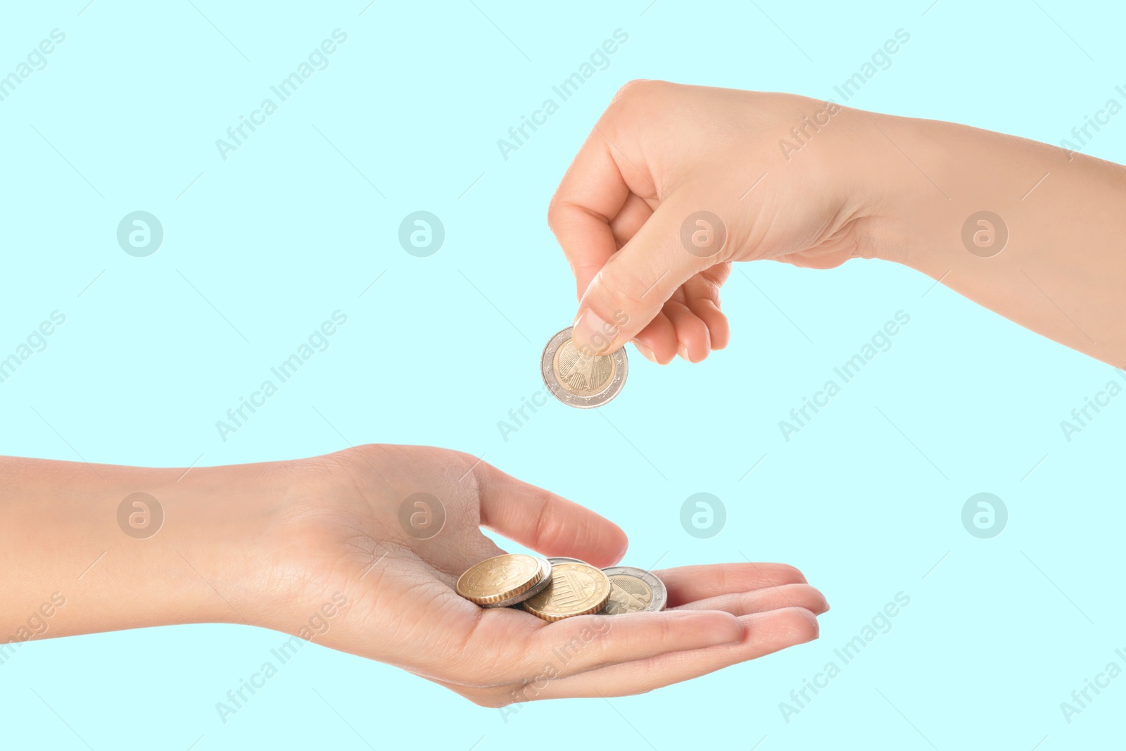 Image of Sponsor offering coins to woman on light blue background, closeup