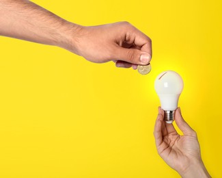 Image of Find sponsor. Man offering coin to woman with light bulb on yellow background, closeup. Sponsorship of idea