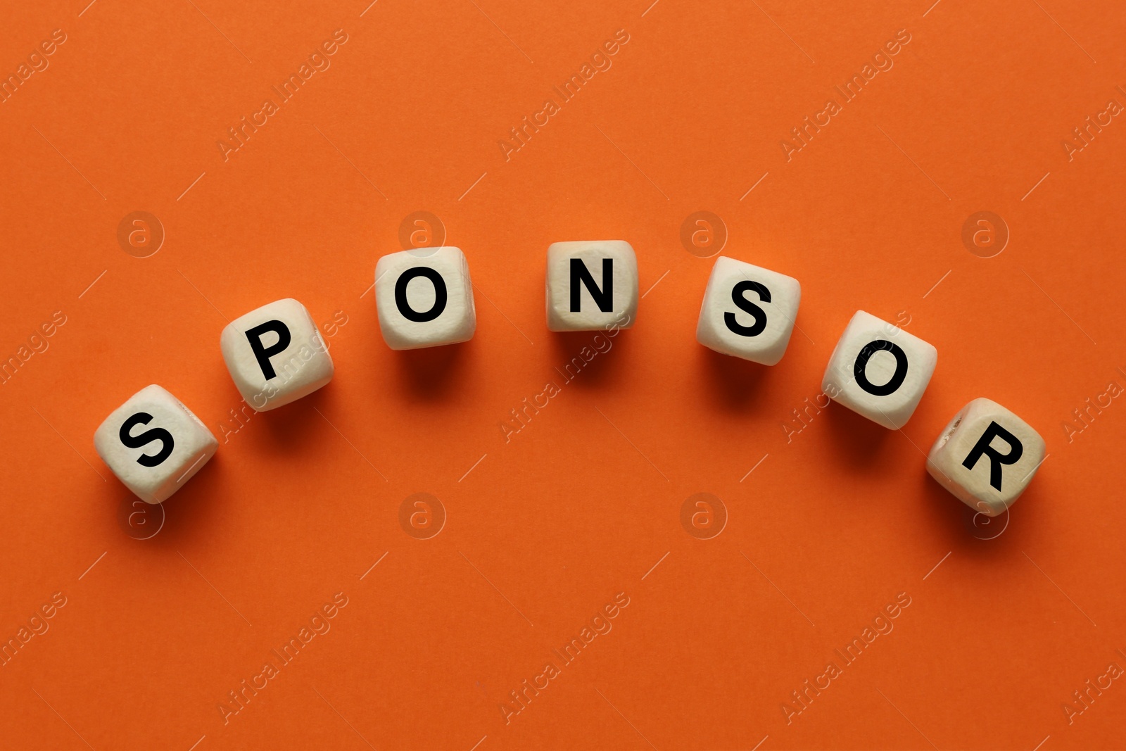 Image of Word Sponsor made of wooden cubes with letters on dark orange background, top view