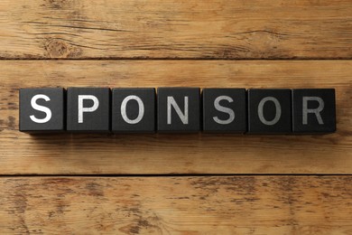 Image of Word Sponsor made of black cubes with letters on wooden background, top view