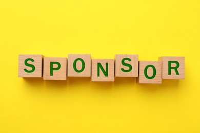 Image of Word Sponsor made of wooden cubes with letters on yellow background, top view