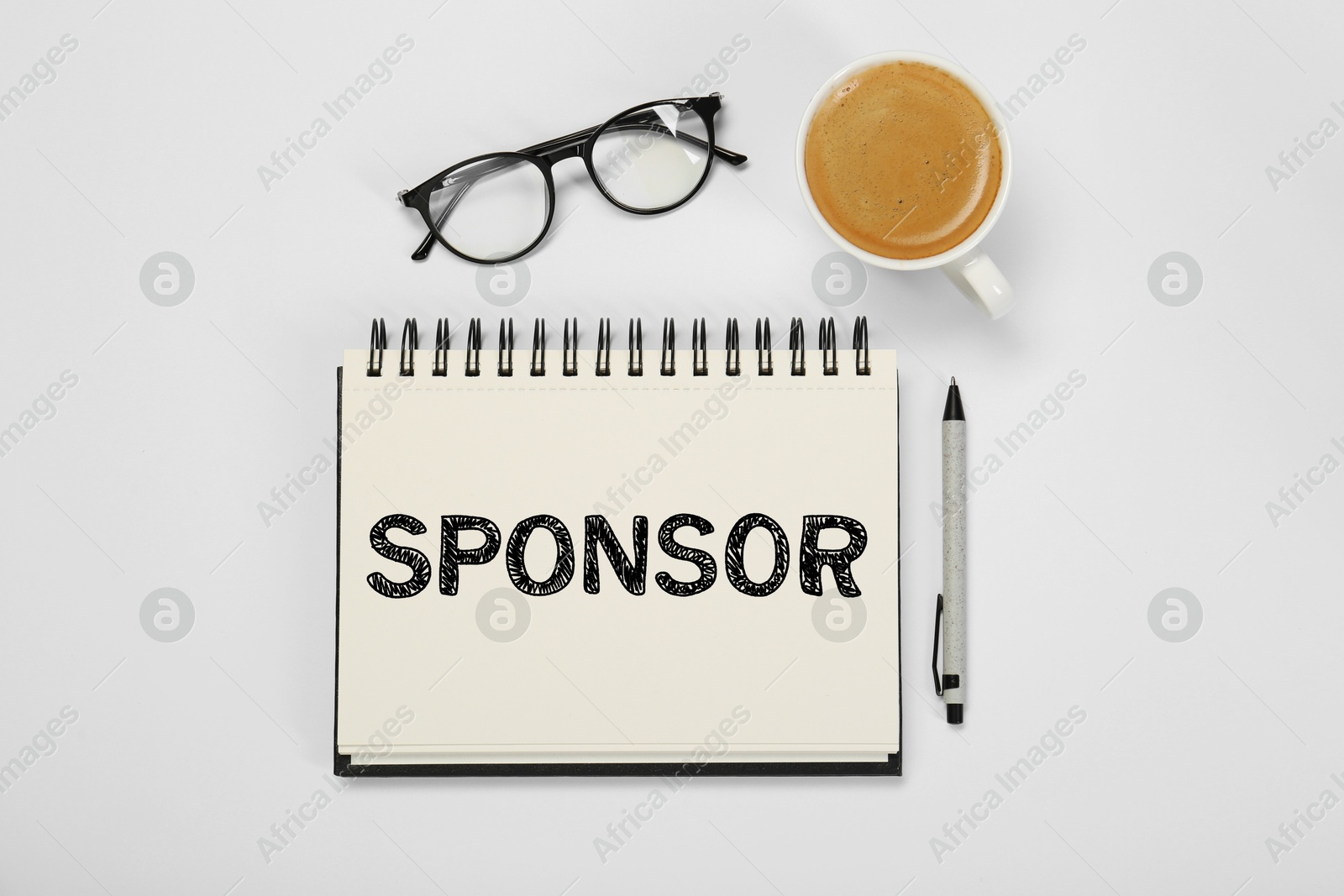 Image of Word Sponsor in notebook, pen, coffee and eyeglasses on white table, top view