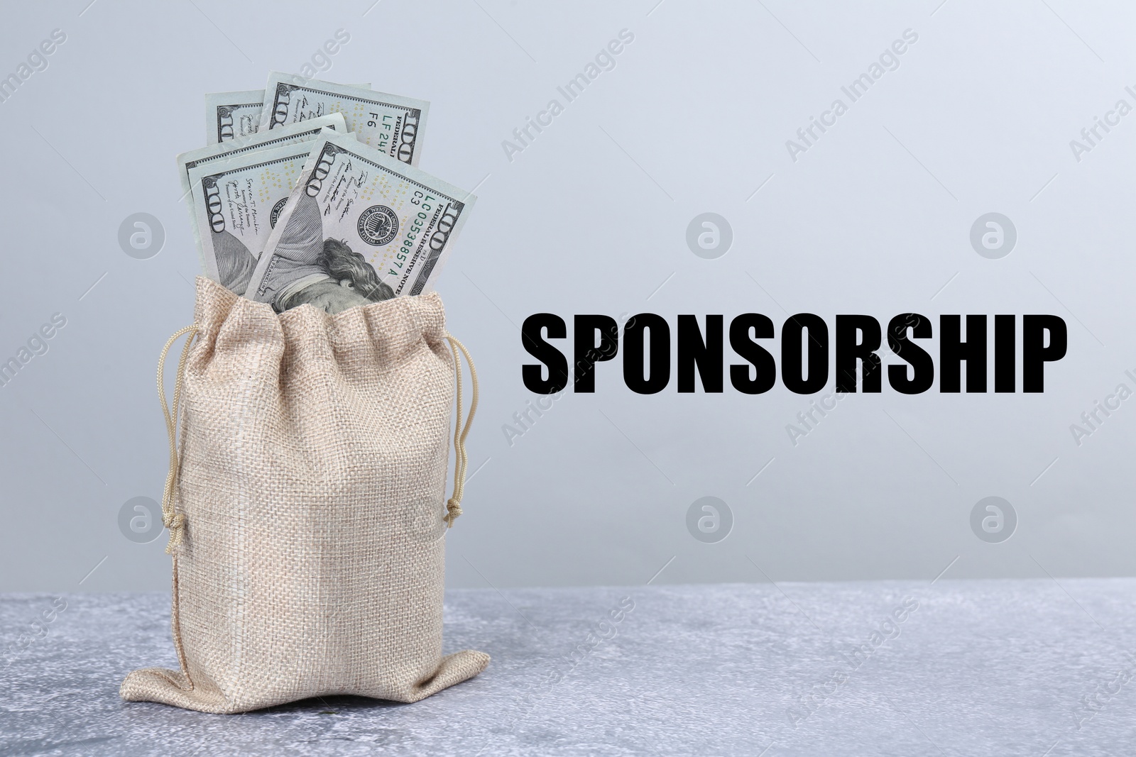 Image of Sponsorship. Sack bag full of dollar banknotes on grey table