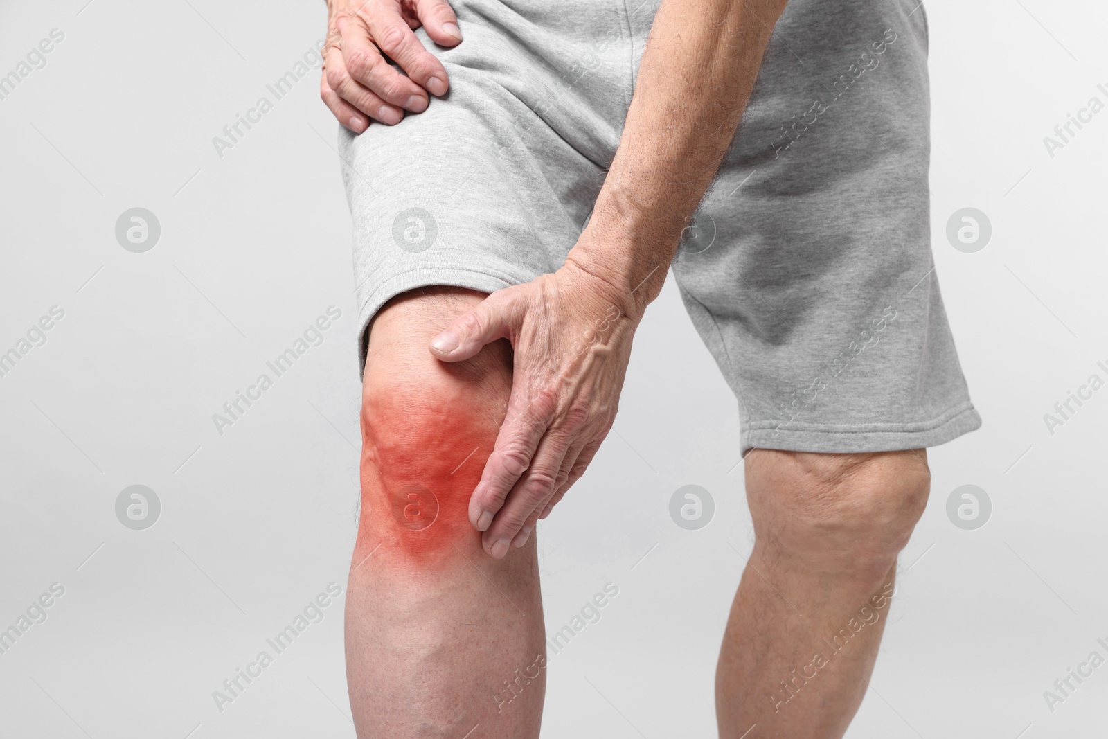 Image of Senior man suffering from pain in knee on light background, closeup