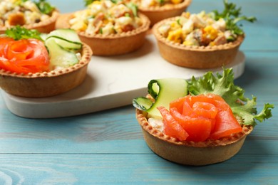 Photo of Tartlets with delicious fillings on blue wooden table, closeup