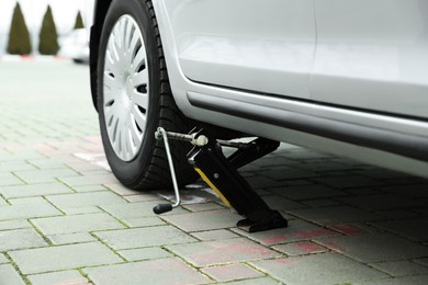 Photo of Car lifted by scissor jack on roadside outdoors