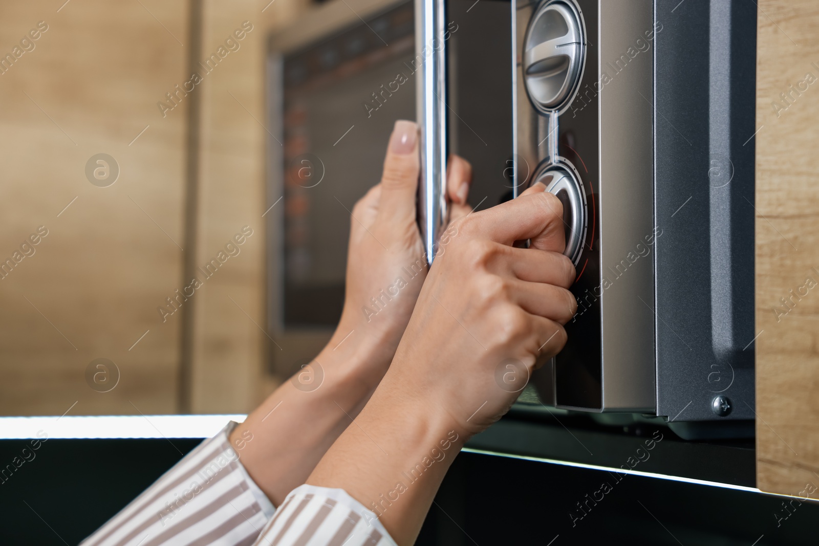 Photo of Woman turning on microwave at home, closeup