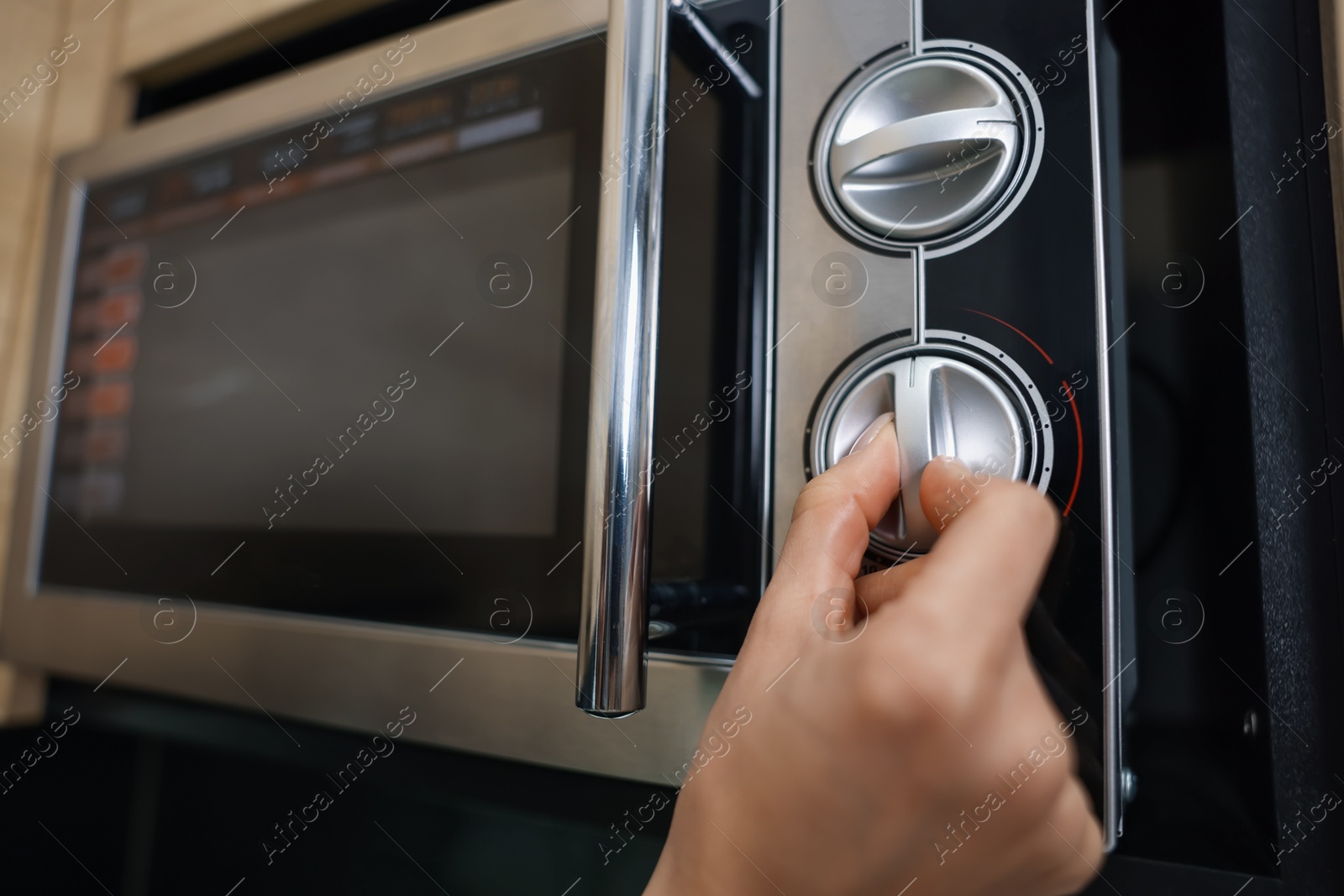 Photo of Woman turning on microwave at home, closeup