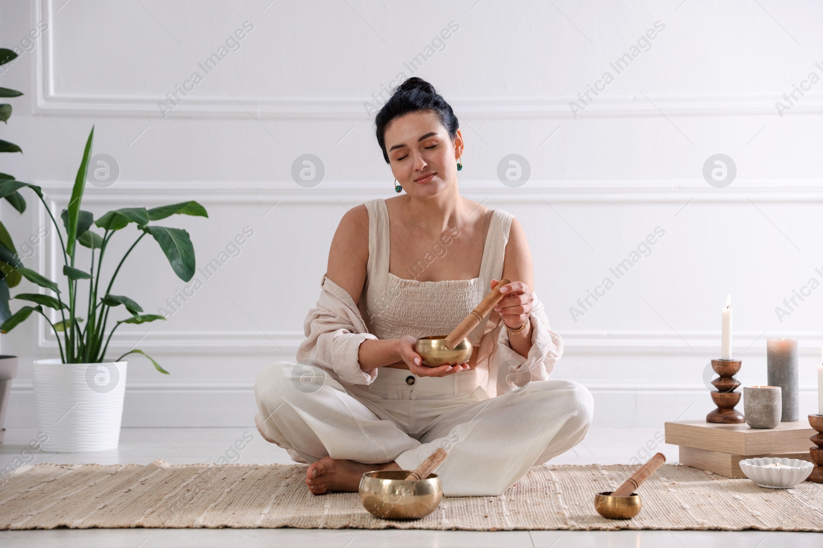 Photo of Woman with singing bowls on floor indoors