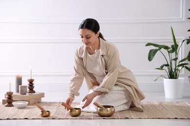 Woman with singing bowls on floor indoors