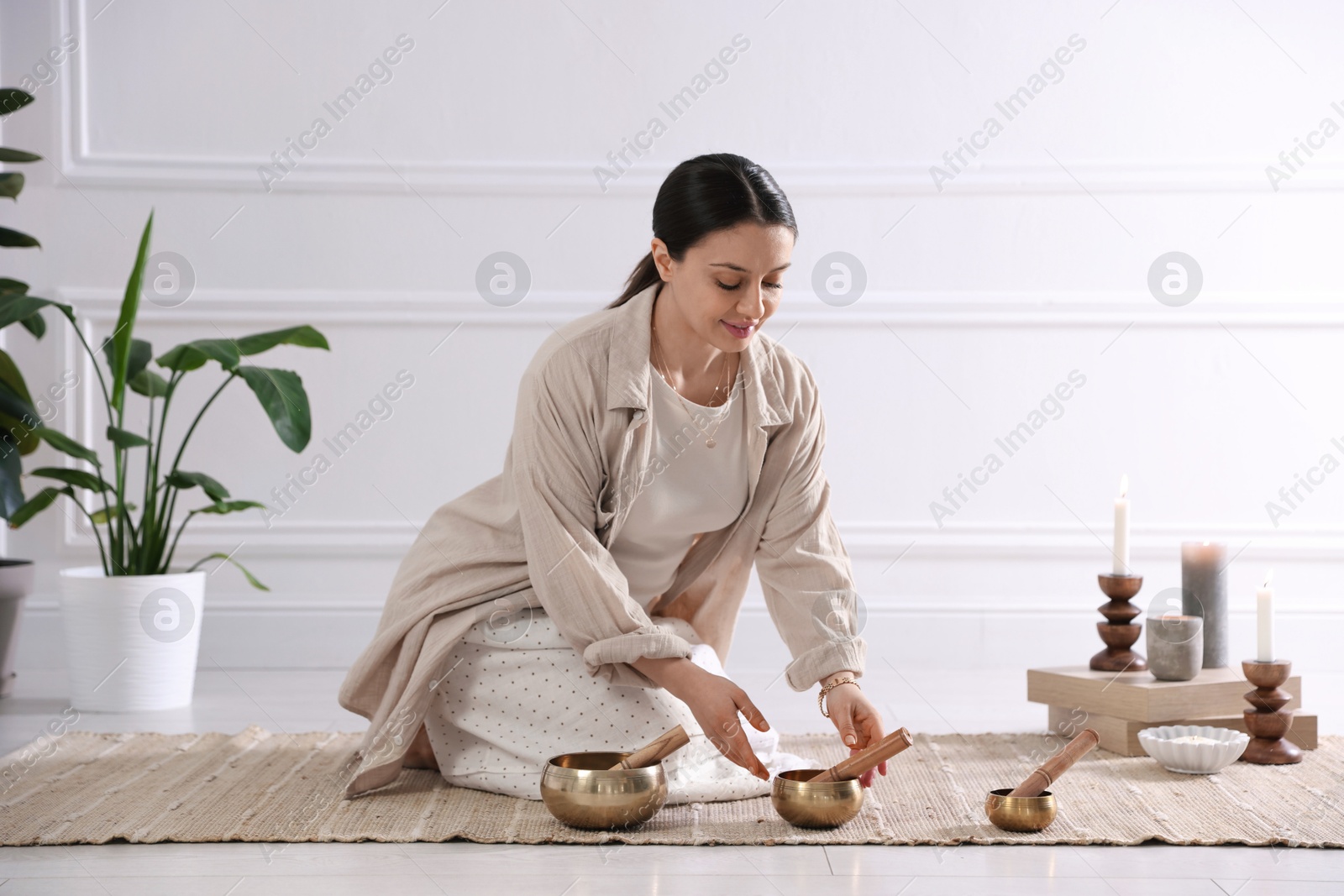 Photo of Woman with singing bowls on floor indoors