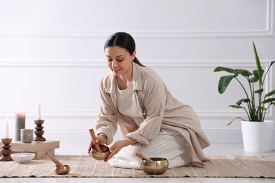 Photo of Woman with singing bowls on floor indoors