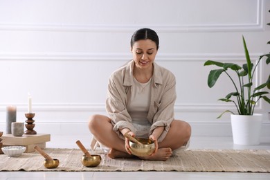 Photo of Woman with singing bowls on floor indoors