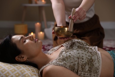 Photo of Woman undergoing singing bowl therapy lying on floor indoors