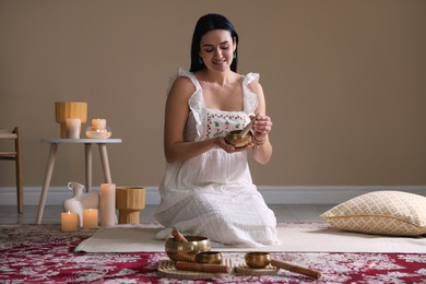 Photo of Woman with singing bowls and burning candles indoors