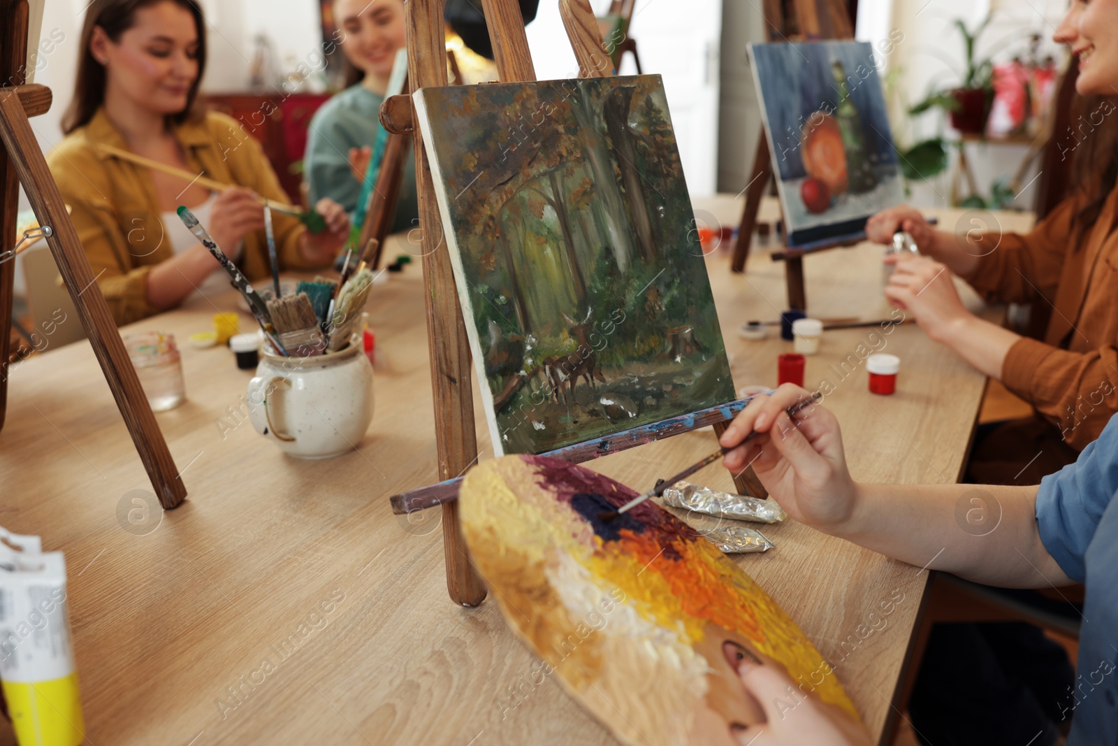 Photo of Group of women learning to draw at wooden table in class, closeup