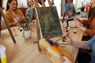 Group of women learning to draw at wooden table in class, closeup