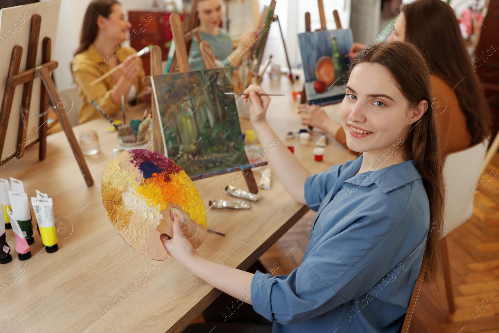 Photo of Group of women learning to draw at wooden table in class