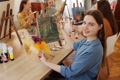 Photo of Group of women learning to draw at wooden table in class