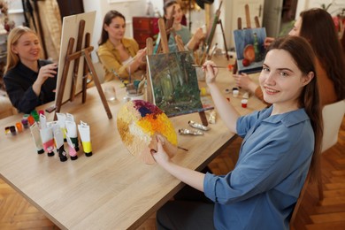 Photo of Group of women learning to draw at wooden table in class